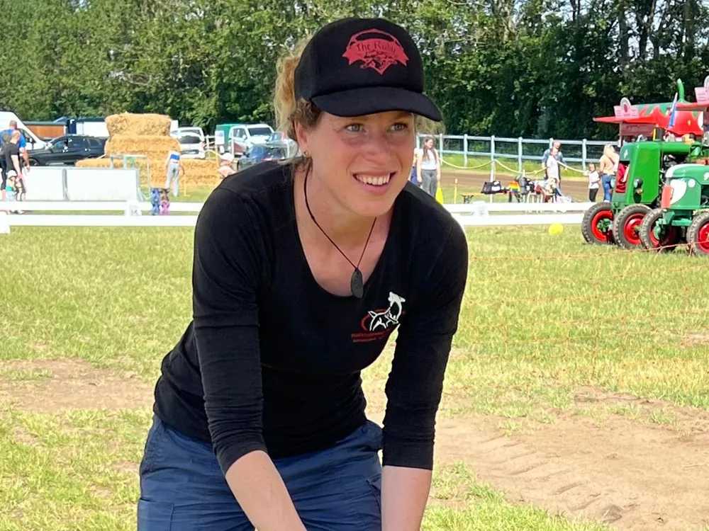Maren lächelt, sie trägt eine schwarze Kappe und steht auf einer Wiese